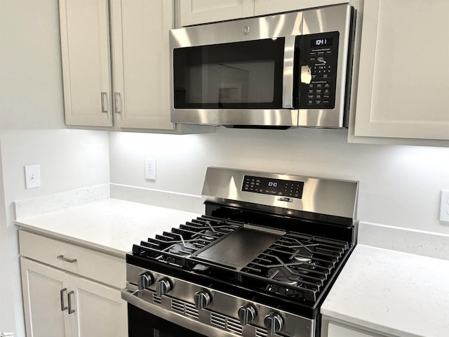 207 Fenner Pl, Greenville, SC 29607 - kitchen with stainless steel appliances, light stone countertops, and white cabinetry