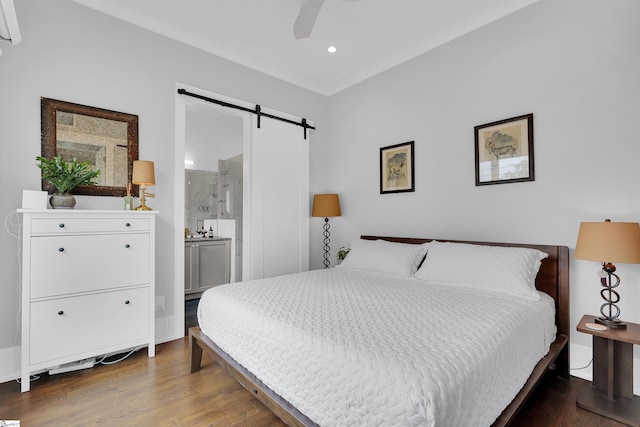 bedroom with a barn door, wood finished floors, recessed lighting, ensuite bathroom, and a ceiling fan