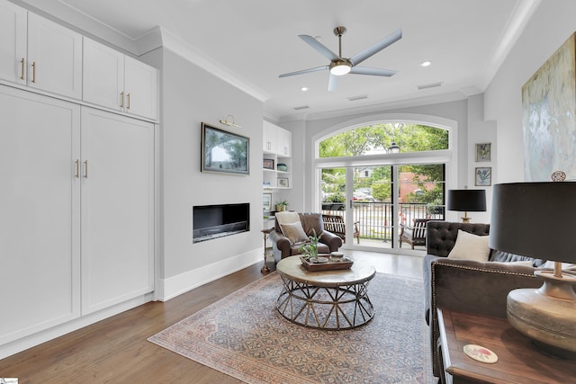 living room featuring a glass covered fireplace, ornamental molding, a ceiling fan, wood finished floors, and recessed lighting