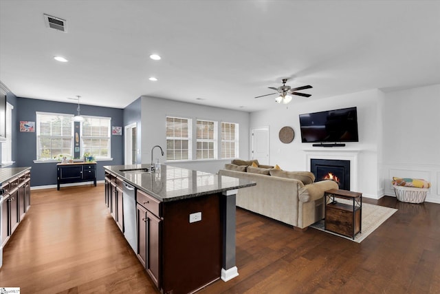 205 Hartwood Lake Ln, Greer, SC 29650 - kitchen featuring a sink, ceiling fan, a warm lit fireplace, dark wood-style flooring, and dark stone counters