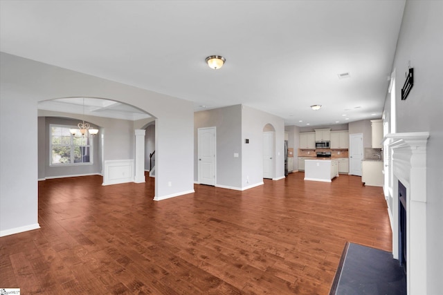 606 N Meadows Ln, Easley, SC 29642 - unfurnished living room with arched walkways, a chandelier, dark wood-style floors, and a fireplace with flush hearth