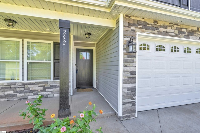 property entrance featuring stone siding, a garage, and a porch