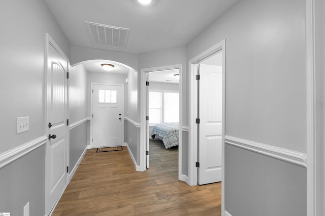 foyer entrance with arched walkways, wood finished floors, and baseboards