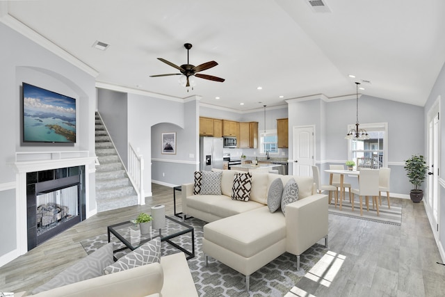 living room with light wood-type flooring, a ceiling fan, stairs, baseboards, and recessed lighting