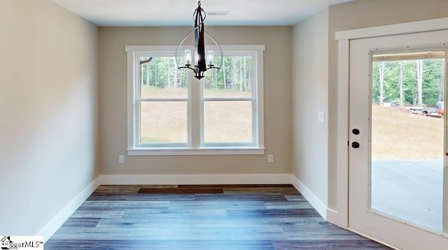unfurnished dining area with a chandelier, plenty of natural light, baseboards, and wood finished floors