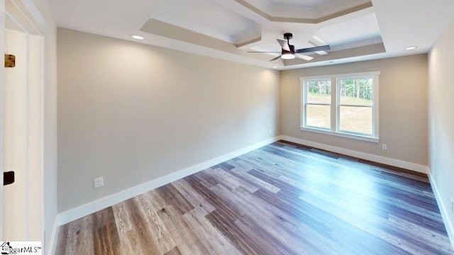 empty room with ceiling fan, wood finished floors, and baseboards