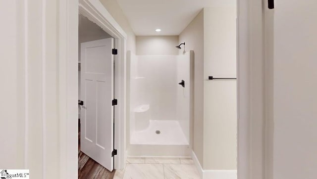 bathroom featuring a shower stall and baseboards