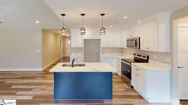 kitchen featuring appliances with stainless steel finishes, a sink, an island with sink, light wood finished floors, and recessed lighting
