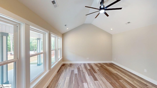 spare room featuring ceiling fan, plenty of natural light, vaulted ceiling, baseboards, and light wood finished floors