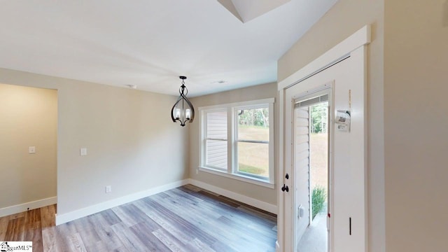unfurnished dining area featuring light wood-type flooring, baseboards, and a chandelier