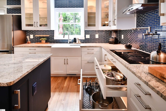210 Cross Field Rd, Greenville, SC 29607 - kitchen featuring black electric cooktop, wall chimney exhaust hood, white cabinetry, freestanding refrigerator, and decorative backsplash