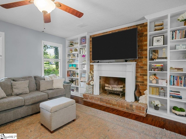 living area featuring wood finished floors, a fireplace, a ceiling fan, and a textured ceiling