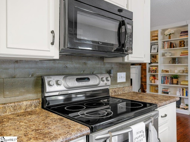 kitchen featuring stainless steel range with electric stovetop, black microwave, white cabinets, decorative backsplash, and ornamental molding