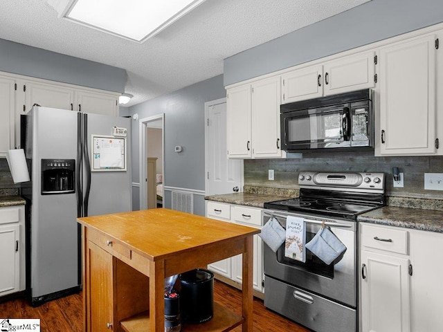 kitchen featuring appliances with stainless steel finishes, dark wood finished floors, white cabinets, decorative backsplash, and dark countertops