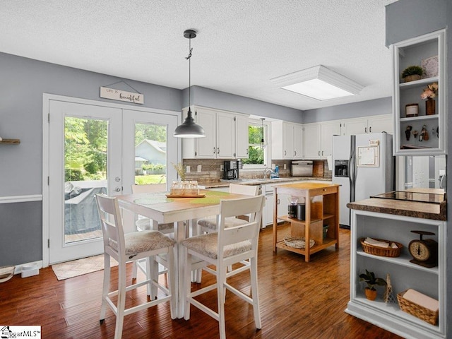 kitchen featuring fridge with ice dispenser, open shelves, a textured ceiling, white cabinetry, and light countertops