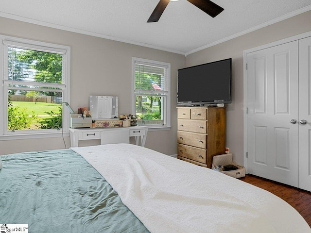 bedroom with crown molding, dark wood finished floors, a ceiling fan, a closet, and a textured ceiling