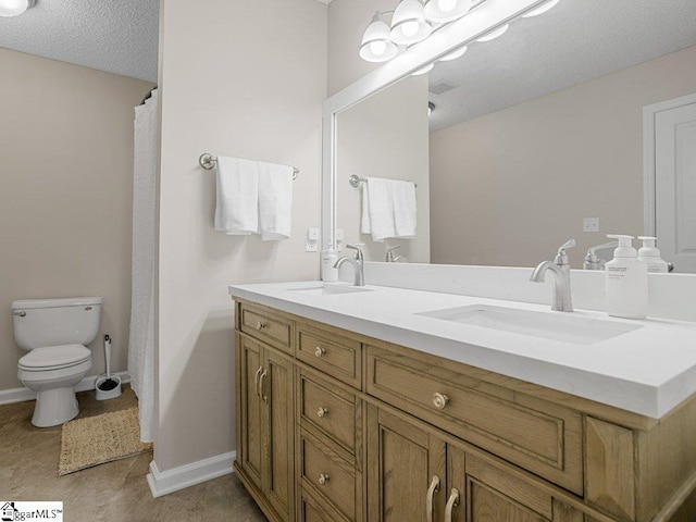 bathroom with toilet, double vanity, and baseboards