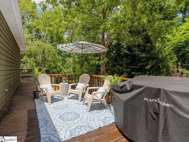 wooden deck with area for grilling and view of wooded area