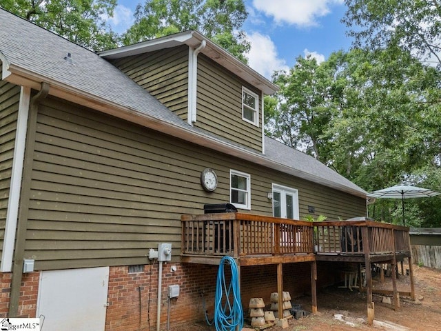 rear view of property featuring a deck and roof with shingles