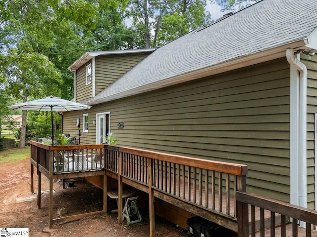 back of house with a wooden deck and roof with shingles