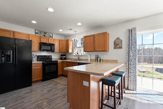 640 Slippery Moss Dr, Spartanburg, SC 29303 - kitchen featuring black appliances, a sink, a peninsula, wood finished floors, and a breakfast bar