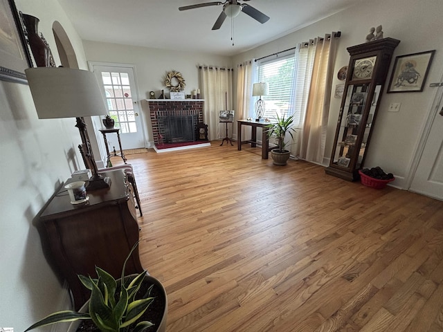 422 E Savannah St, Calhoun Falls, SC 29628 - living area with light wood finished floors, a ceiling fan, and a brick fireplace