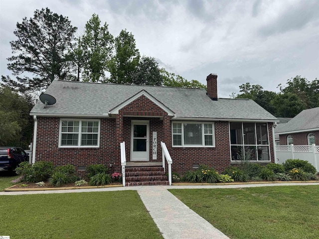 422 E Savannah St, Calhoun Falls, SC 29628 - view of front of house with brick siding, a chimney, a sunroom, and roof with shingles