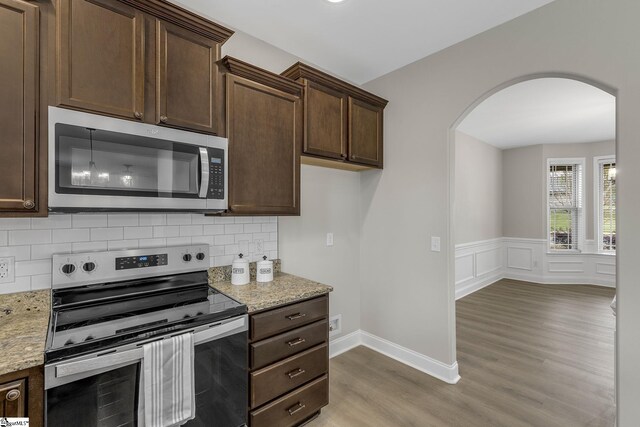9 Amber Oaks Dr, Greer, SC 29651 - kitchen featuring appliances with stainless steel finishes, arched walkways, wood finished floors, dark brown cabinets, and a wainscoted wall