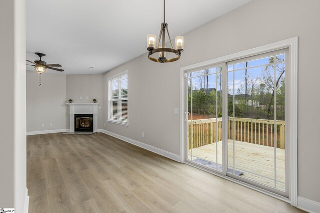 9 Amber Oaks Dr, Greer, SC 29651 - unfurnished living room with wood finished floors, a chandelier, a fireplace with flush hearth, and baseboards