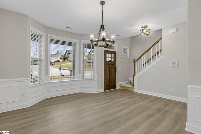 9 Amber Oaks Dr, Greer, SC 29651 - foyer entrance featuring a chandelier, light wood finished floors, wainscoting, stairway, and a decorative wall