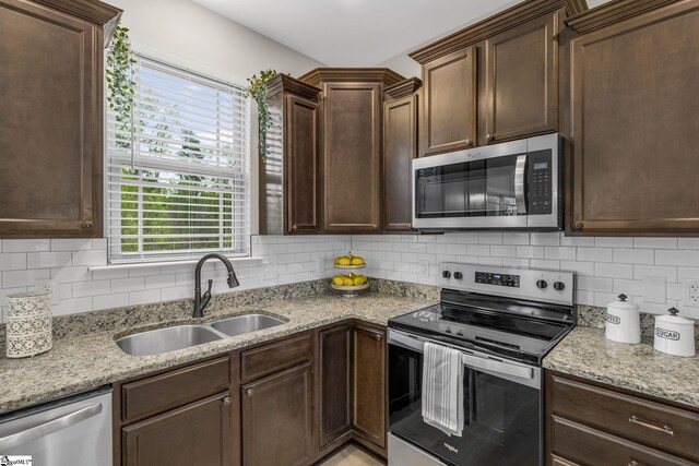 9 Amber Oaks Dr, Greer, SC 29651 - kitchen featuring appliances with stainless steel finishes, a sink, dark brown cabinetry, tasteful backsplash, and light stone countertops