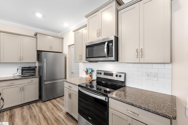 319 Sudduth Farms Dr, Greer, SC 29650 - kitchen featuring appliances with stainless steel finishes, ornamental molding, tasteful backsplash, light wood-type flooring, and dark stone countertops