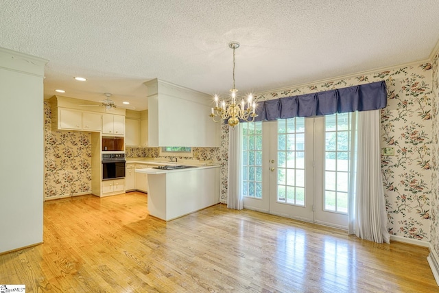 129 E Main St, Duncan, SC 29334 - kitchen featuring black oven, wallpapered walls, a textured ceiling, a peninsula, and light wood finished floors