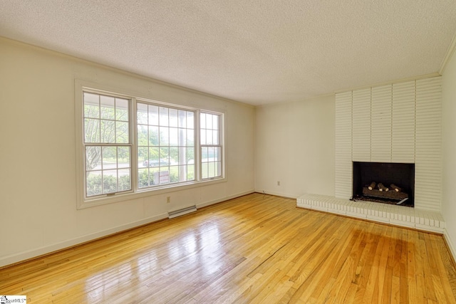 129 E Main St, Duncan, SC 29334 - unfurnished living room featuring a textured ceiling, wood finished floors, a baseboard heating unit, a brick fireplace, and baseboards