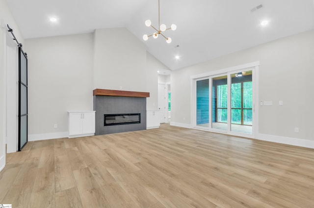 120 Thomason View Rd, Fountain Inn, SC 29644 - unfurnished living room featuring high vaulted ceiling, a barn door, a chandelier, light wood-style flooring, and a glass covered fireplace