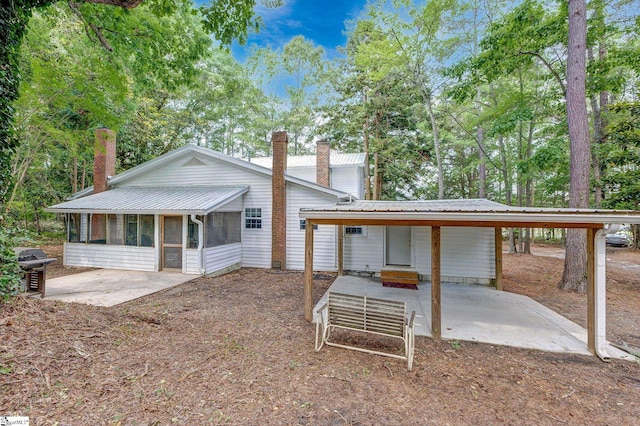 2444 Abner Creek Rd, Duncan, SC 29334 - back of property with a chimney, a sunroom, metal roof, a patio area, and a carport