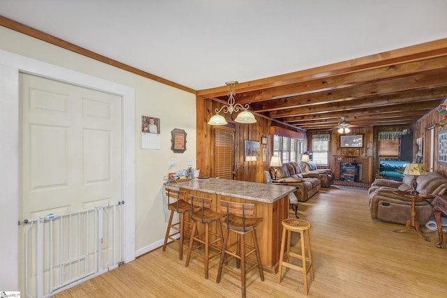 600 Gulliver St, Fountain Inn, SC 29644 - kitchen featuring light wood-style floors, a breakfast bar area, a peninsula, hanging light fixtures, and wood walls