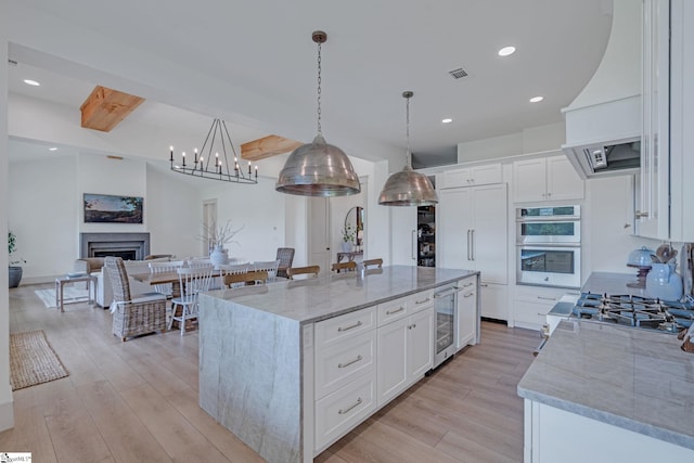 320 Terry Rd, Fountain Inn, SC 29644 - kitchen featuring beverage cooler, beamed ceiling, light wood-type flooring, stainless steel appliances, and light stone countertops