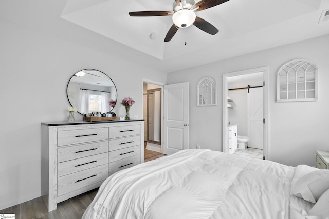 2606 Karkinnen Way, Moore, SC 29369 - bedroom with a tray ceiling, a barn door, wood finished floors, baseboards, and connected bathroom