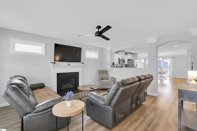 116 Bruinen Dr, Fountain Inn, SC 29644 - living area featuring a ceiling fan, a glass covered fireplace, light wood finished floors, arched walkways, and decorative columns