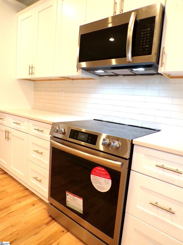 291 Robbins Rd, Chesnee, SC 29323 - kitchen featuring appliances with stainless steel finishes, light countertops, light wood-style flooring, decorative backsplash, and white cabinets