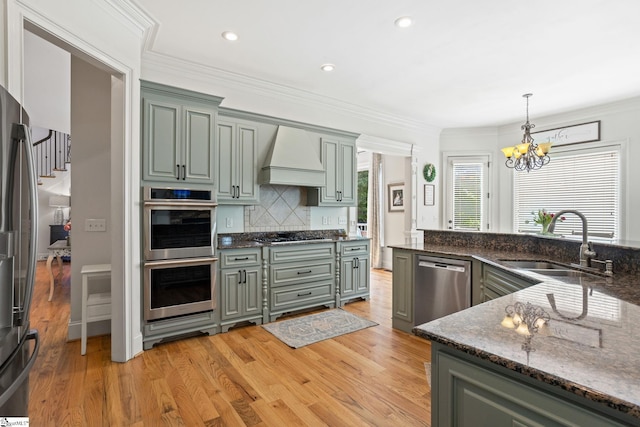 1 Riverstone Way, Greer, SC 29651 - kitchen with stainless steel appliances, a sink, custom range hood, a chandelier, and light wood-type flooring