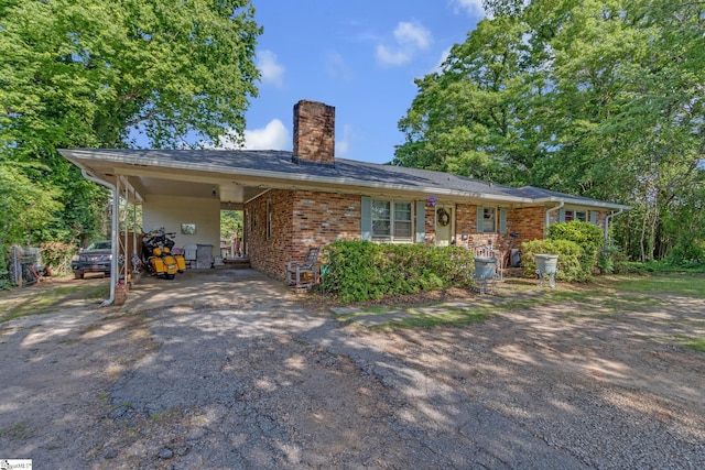 273 Cedar Springs Rd, Spartanburg, SC 29302 - view of front of house featuring dirt driveway, a chimney, brick siding, and a carport