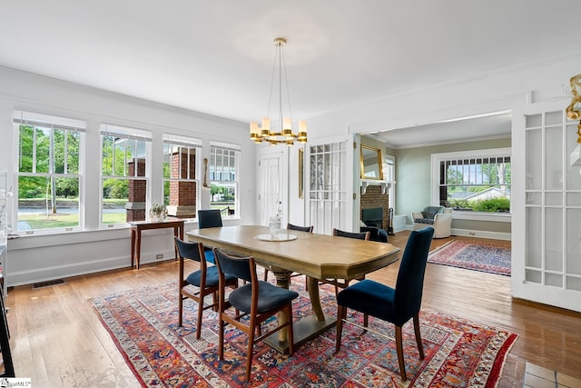 227 S Main St, Anderson, SC 29654 - dining area featuring crown molding, a chandelier, wood-type flooring, a fireplace, and baseboards
