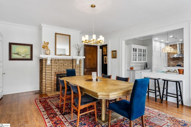 227 S Main St, Anderson, SC 29654 - dining area with a chandelier, wood finished floors, ornamental molding, and a brick fireplace