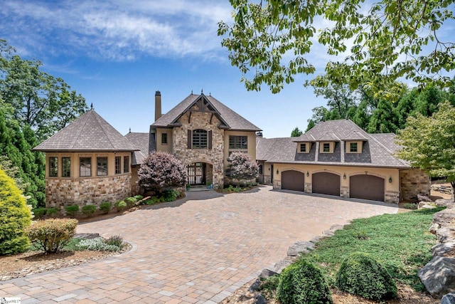 58 Wild Ginger Rd, Landrum, SC 29356 - french provincial home with stone siding, a garage, a chimney, decorative driveway, and stucco siding