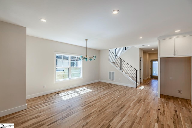 11 Stall St, Greenville, SC 29609 - unfurnished living room with light wood finished floors, stairway, baseboards, and recessed lighting