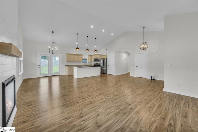 624 Renita Dr, Boiling Springs, SC 29316 - unfurnished living room featuring a chandelier, high vaulted ceiling, a glass covered fireplace, light wood-style floors, and baseboards