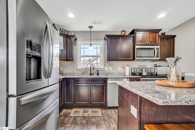 105 Devonfield Dr, Greer, SC 29651 - kitchen featuring appliances with stainless steel finishes, a sink, light wood finished floors, dark brown cabinets, and pendant lighting