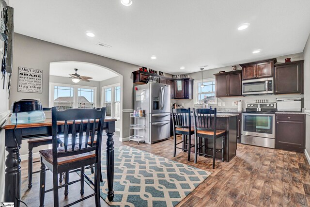 105 Devonfield Dr, Greer, SC 29651 - kitchen featuring appliances with stainless steel finishes, arched walkways, dark brown cabinets, a breakfast bar area, and a kitchen island